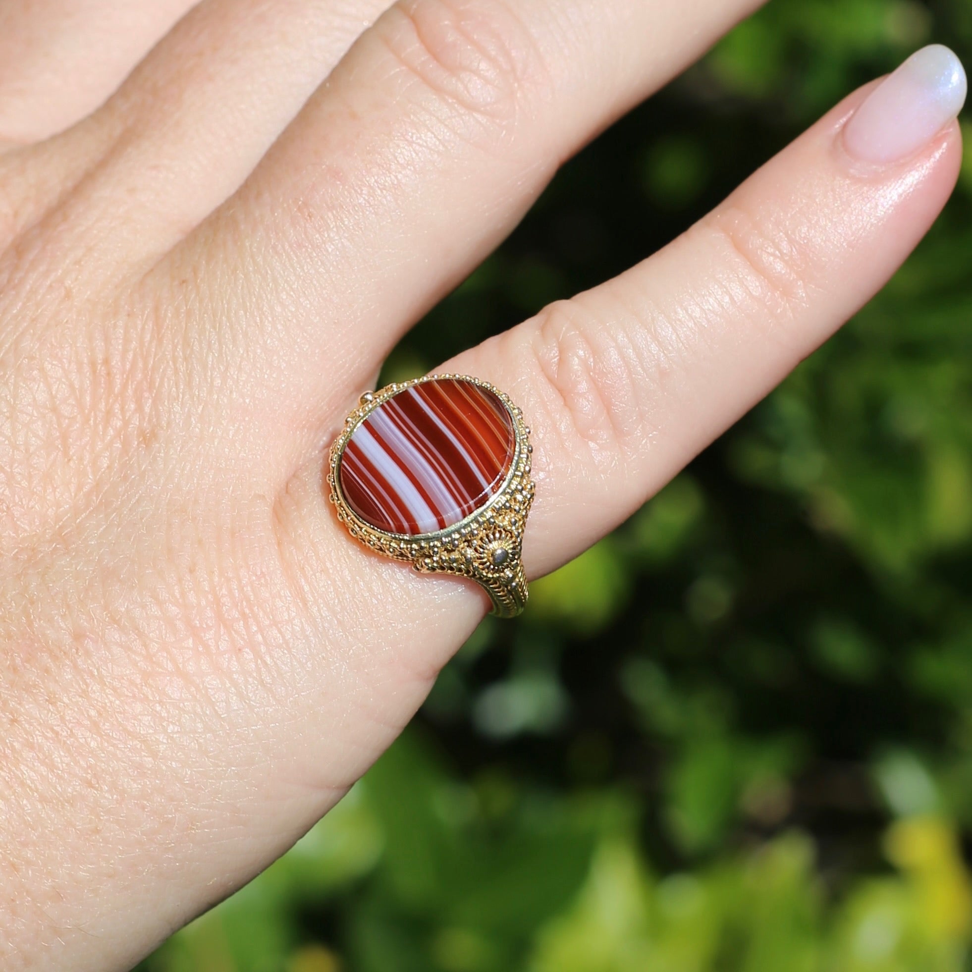 This ring is a banded agate popular size 8. It is bordered by bead wire and set in a gallery bezel. It has a heart design band